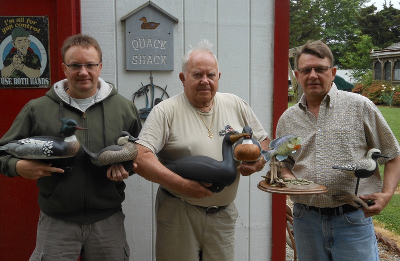 Richard Belote began carving duck decoys in 1951 out of necessity: he wanted to go hunting. That need turned into a passion that he's passed down to his sons, Ames and Scott. Standing in front of Richard's shop, called the Quack Shack, in Lewes with a few of their award-winning carvings are (l-r) Scott, holding a red-breasted merganser drake and a ruddy duck; Richard holding a cormorant and a red-breasted merganser drake; and Ames holding a blue gill sunfish and a black belly plover. BY CHRIS FLOOD